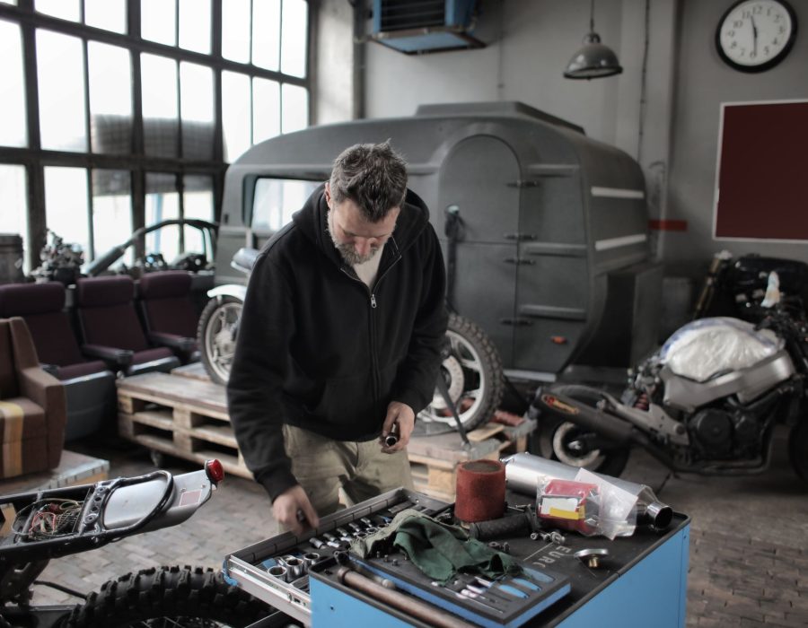 Mechaniker arbeitet in einer Werkstatt an der Werkbank mit Werkzeugen