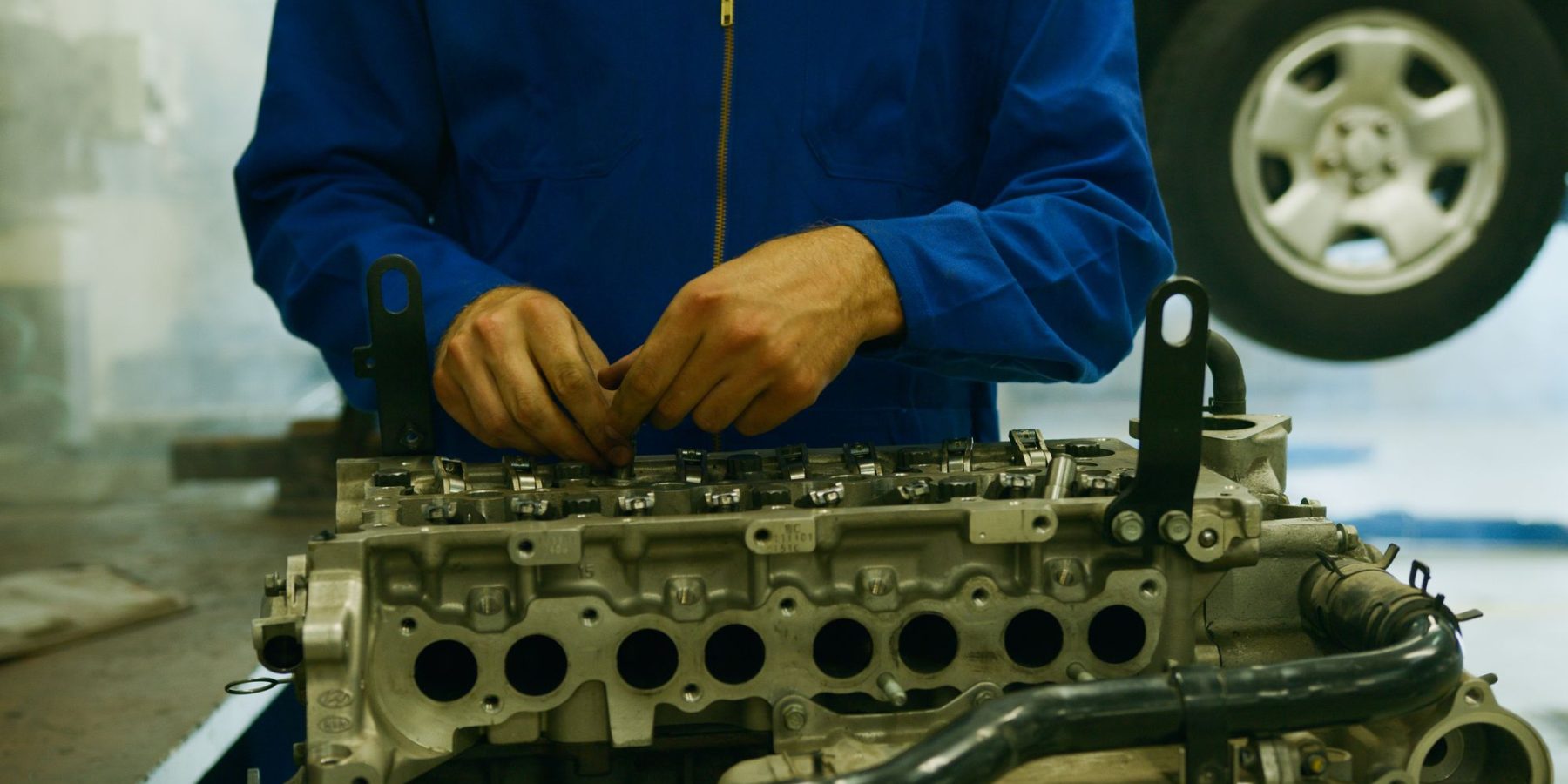 Mechaniker-Hände arbeiten an einem ausgebauten Zylinderkopf